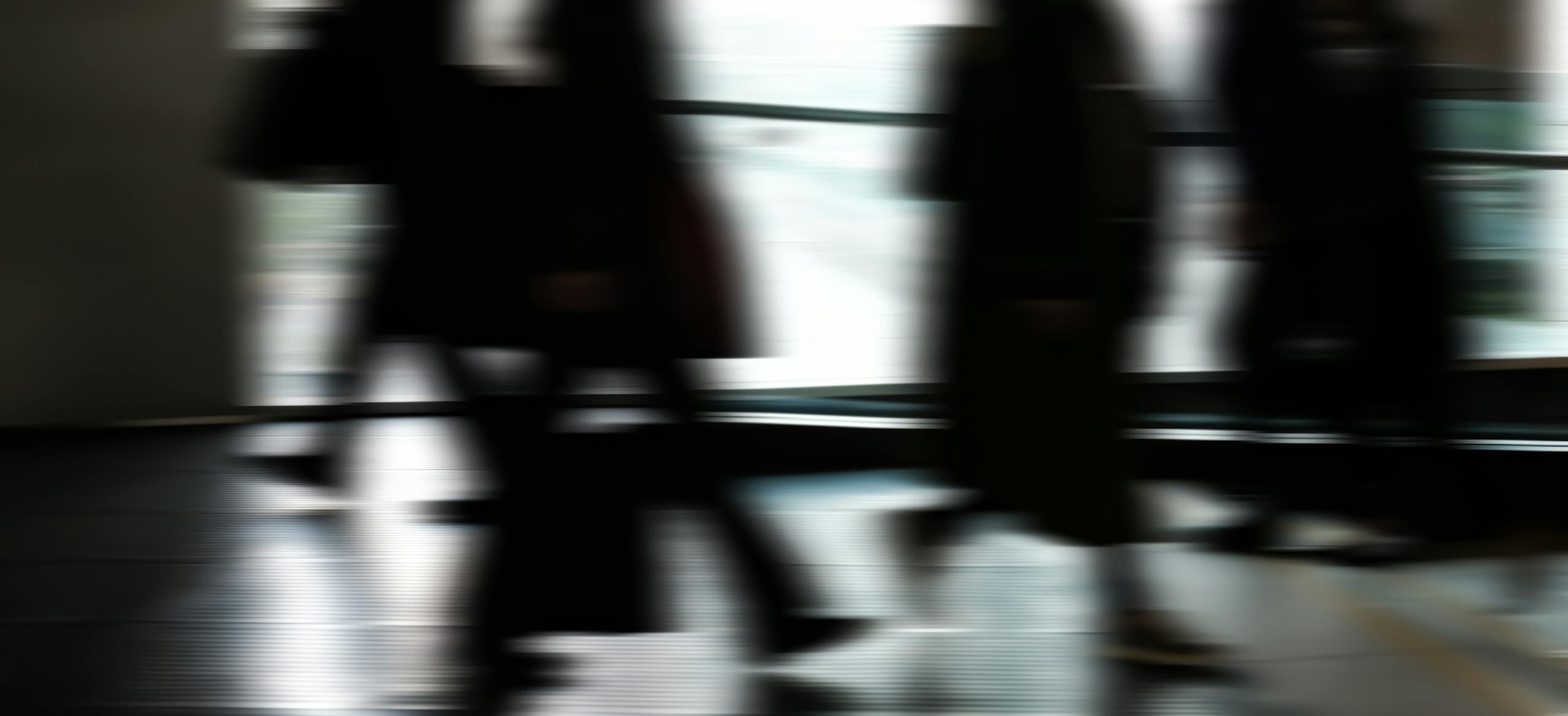 Abstract blurred motion of people walking indoors, depicting urban life and busy routines.